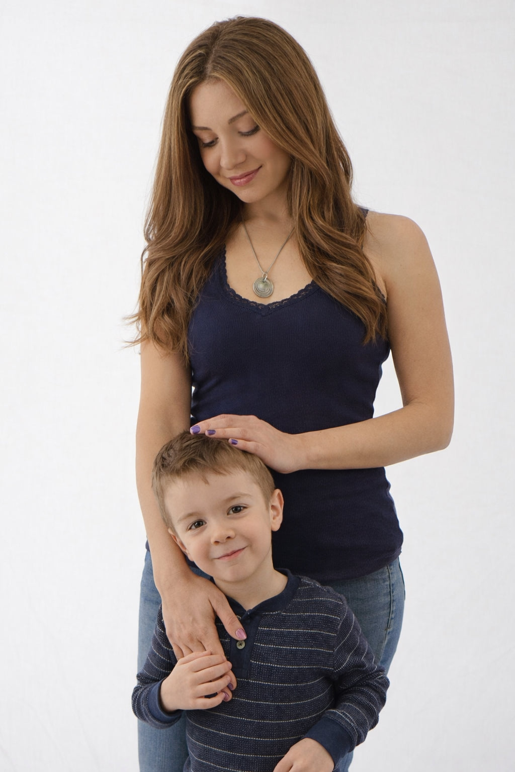 Woman and young boy standing close together on a white background