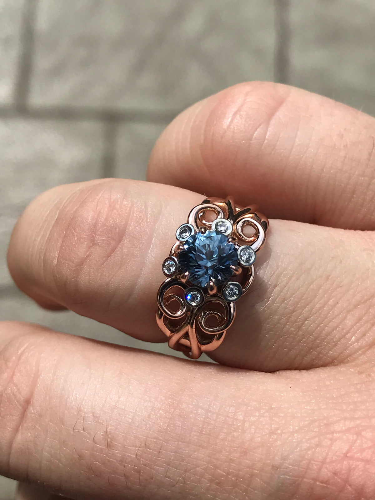 A handmade custom sapphire and diamond gold ring on finger