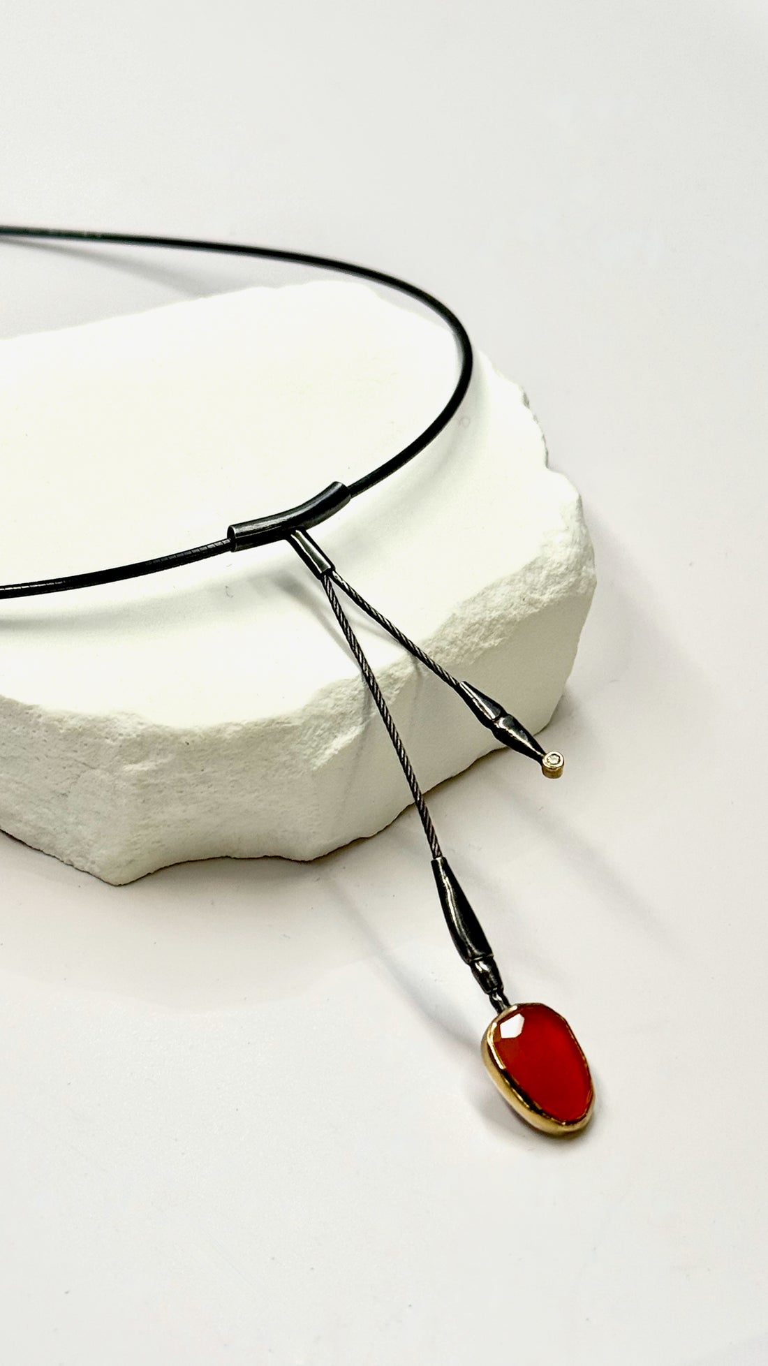 Necklace with a red pendant on a white stone surface