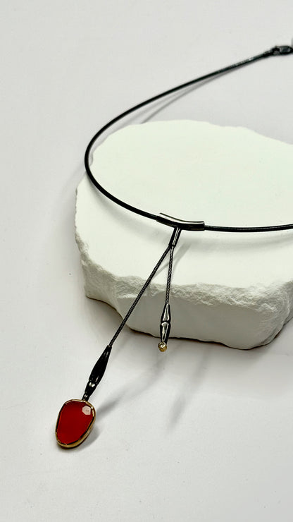 Necklace with a red pendant on a white stone surface