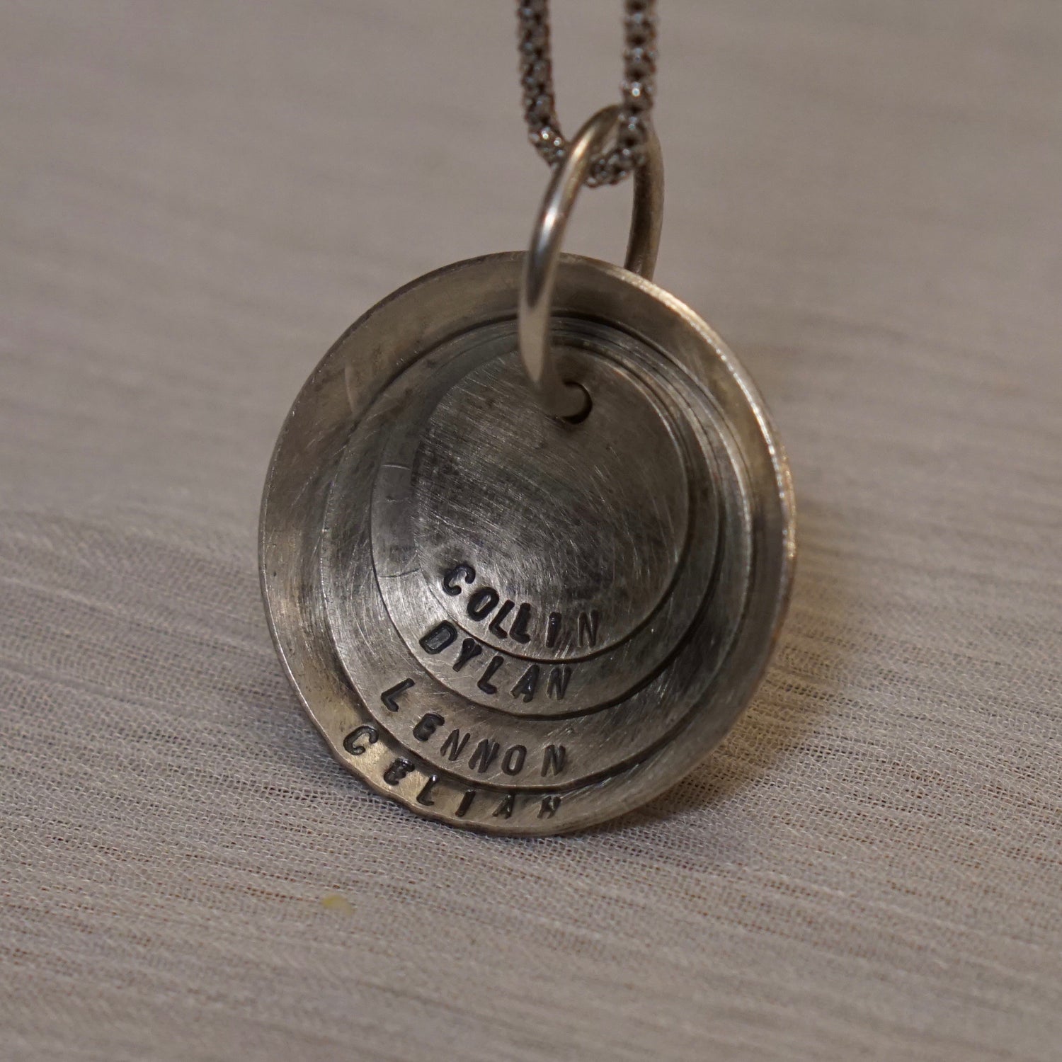 A nesting disc necklace that can be personalized with dates and names of family members or pets