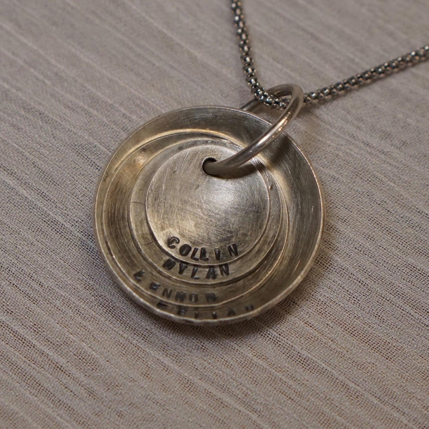 A nesting disc necklace that can be personalized with dates and names of family members or pets